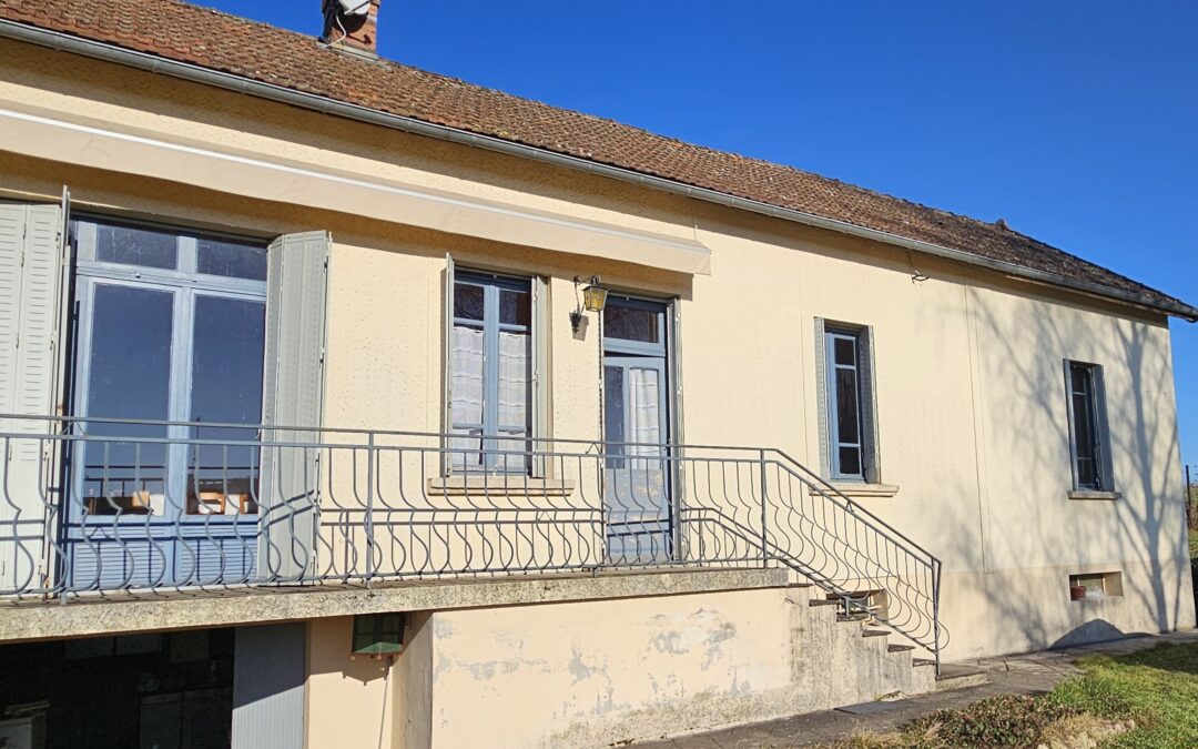 Façade de maison beige avec balcon et volets bleus