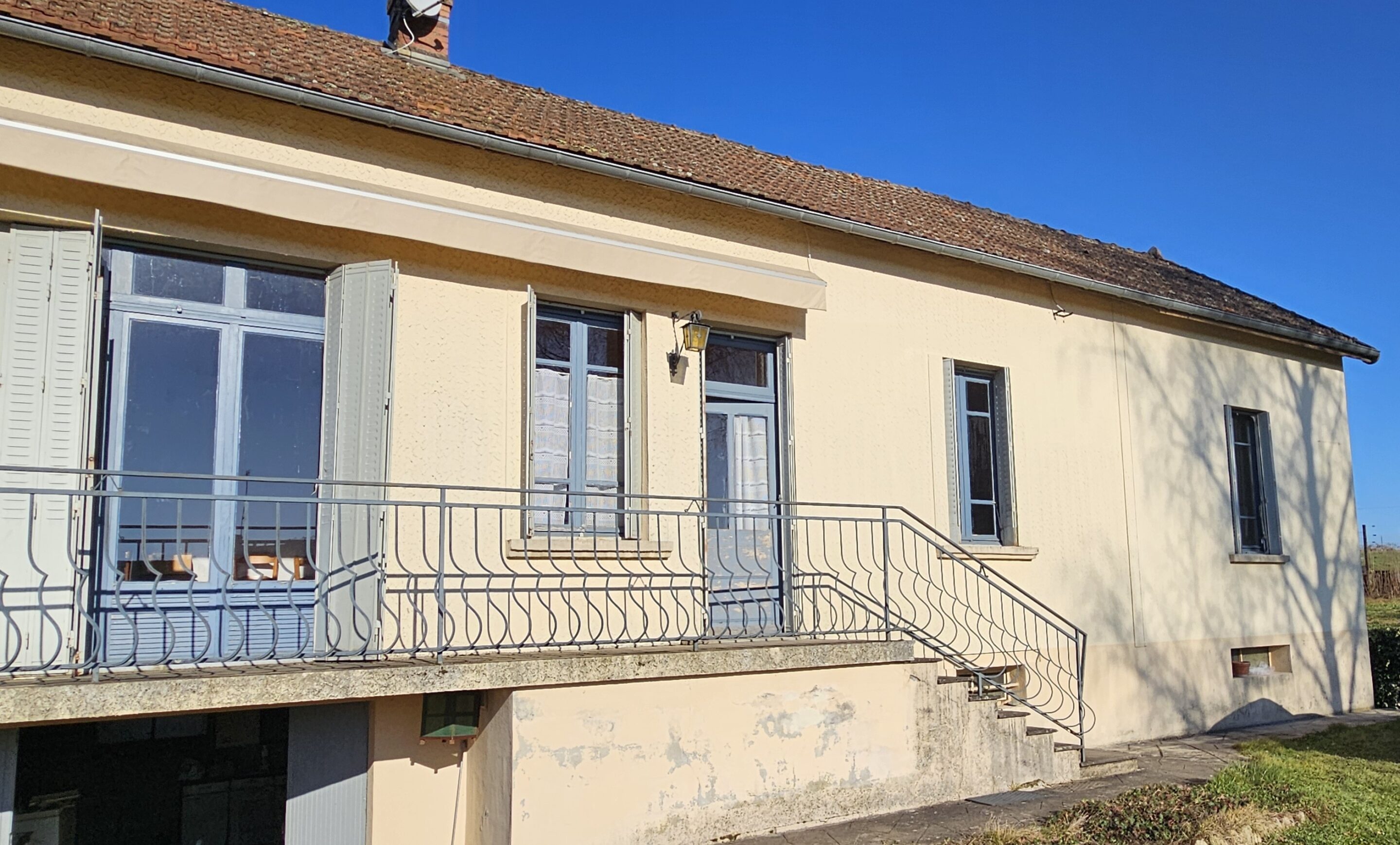 Façade de maison beige avec balcon et volets bleus